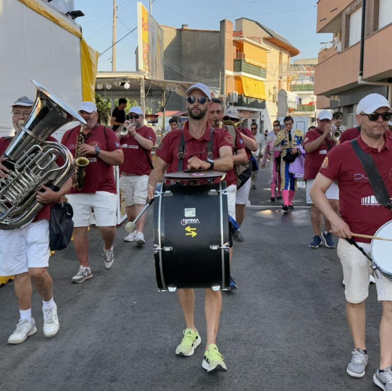 Una charanga o banda musical desfilando por una calle de El Boalo, con músicos tocando instrumentos de viento y percusión, creando un ambiente festivo tradicional en las Fiestas anuales.