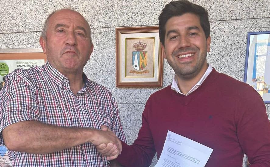Sergio Yunquera - se dan la mano sonriendo, uno recibe un documento, sugiriendo un acuerdo o reconocimiento formal.