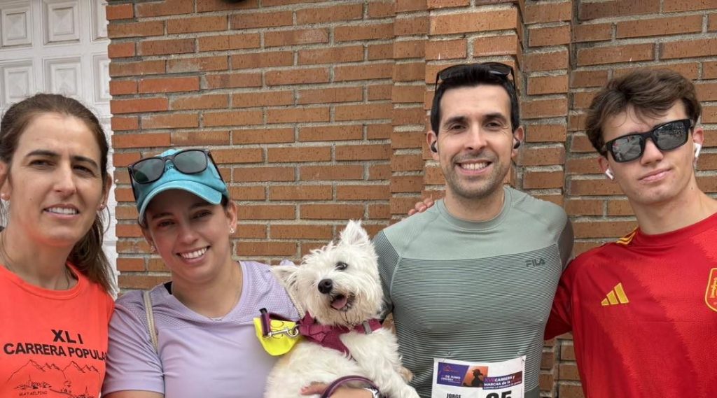 Cuatro personas y un perro posan sonrientes tras una carrera. Un equipo incondicional.