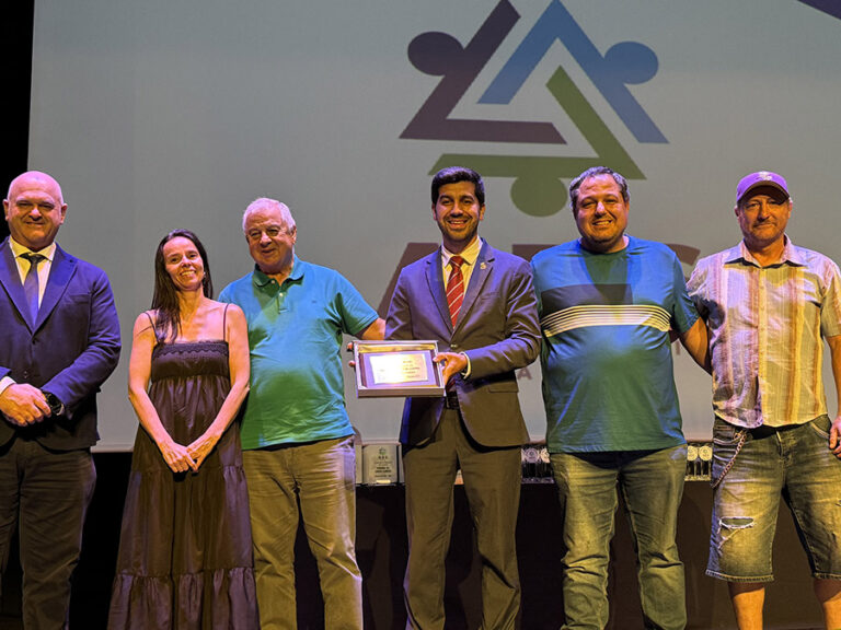 Sergio Yunquera, Presidente de ADS y Alcalde de El Boalo (centro, con traje), entrega un premio a un grupo de hombres en el escenario de la XV Gala del Deporte ADS, con el logo de ADS al fondo.
