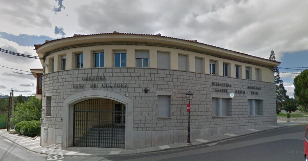 Fachada exterior de la Casa de la Cultura de Cerceda, un edificio de piedra con forma semicircular, ventanas y la inscripción "CERCEDA CASA DE CULTURA" y "BIBLIOTECA MUNICIPAL CARMEN MARTÍN GAITE".