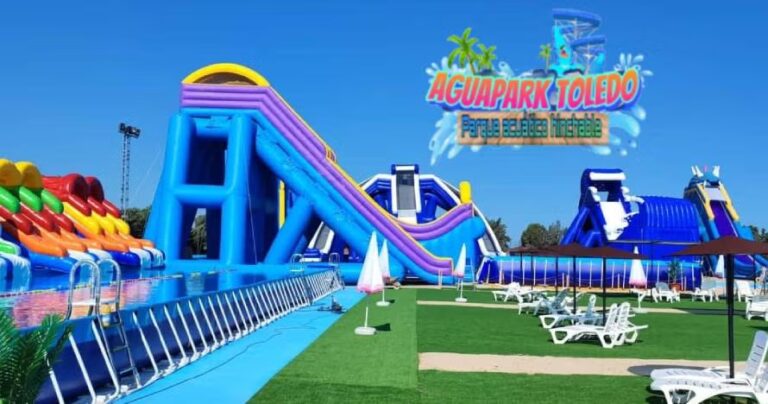 Amplia vista panorámica de AguaPark Toledo, un gran parque acuático hinchable con múltiples toboganes y estructuras flotantes en piscinas, bajo un cielo azul brillante.