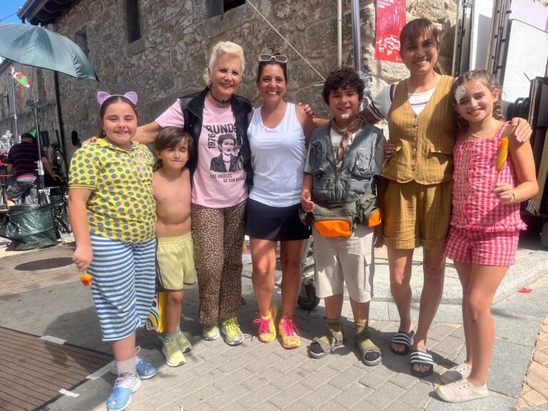 Un grupo de adultos y niños, algunos con vestuario y maquillaje de película, posando sonrientes al aire libre, probablemente actores o participantes en el rodaje de "Abuela Tremenda".