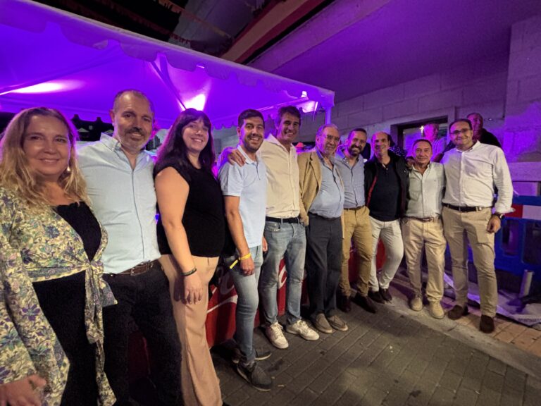 Grupo de hombres y mujeres, incluyendo al alcalde Sergio Yunquera (sexto desde la izquierda) y otros representantes municipales, posando sonrientes bajo iluminación festiva, durante las Fiestas de Verano de Cerceda.