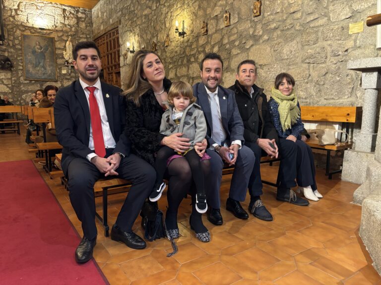 Un grupo de personas, incluyendo al Alcalde Sergio Yunquera (segundo desde la izquierda) y su familia, sentadas en un banco de piedra dentro de una iglesia, durante las celebraciones de San Sebastián en El Boalo, Cerceda y Mataelpino.