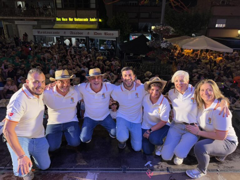 Grupo de siete personas, incluyendo al alcalde Sergio Yunquera y concejales de El Boalo, Cerceda y Mataelpino, posando en un escenario con sombreros de paja y camisetas blancas, con una multitud al fondo durante las Fiestas de El Boalo.