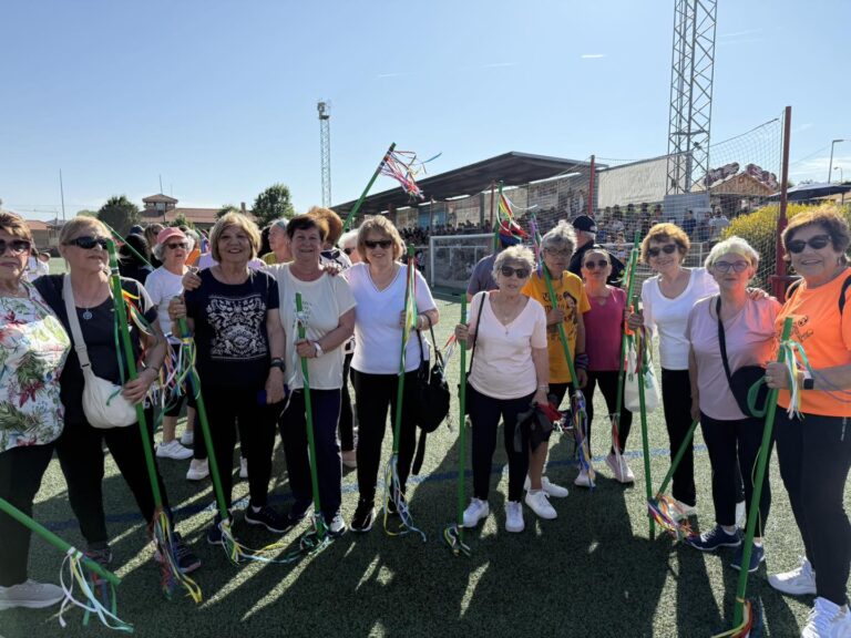 Grupo de mujeres mayores sonrientes, algunas con bastones decorados con cintas de colores, participando activamente en la clausura de la temporada deportiva en El Boalo, Cerceda y Mataelpino.