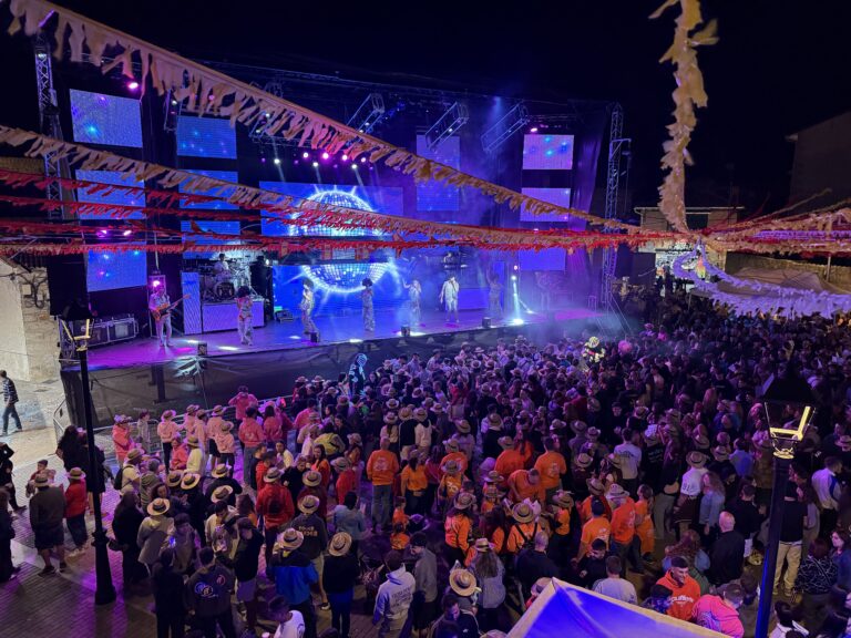 imagen capturó la energía de la noche festiva. Un escenario con una banda en directo, equipada con luces de colores y efectos visuales, fue el punto focal de la celebración nocturna. La multitud se agolpó frente al escenario, disfrutando de la música y el ambiente festivo, en lo que pareció ser un multitudinario concierto.