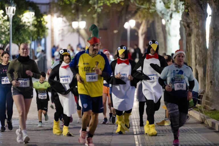 Corredores listos en la línea de salida de una carrera popular, con un cartel con el mensaje "CORRER SIN MIEDO Y NO CORRER POR MIEDO".